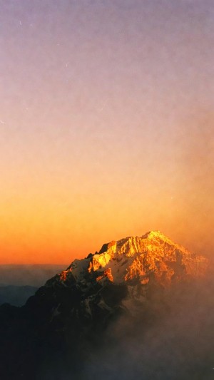Golden mountain peak rising above the clouds at dawn